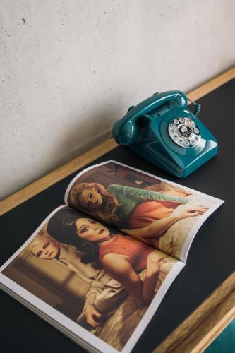 a table with a magazine and a blue purse and a clock at KOPSTER Hotel Residence Paris Ouest Colombes in Colombes