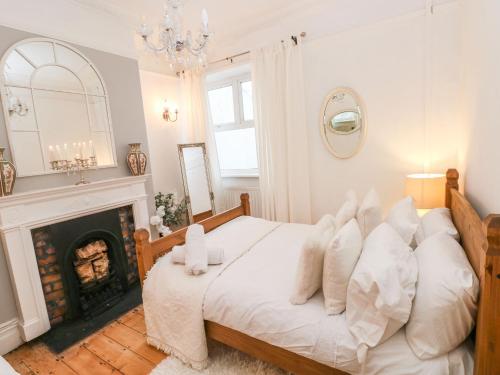 um quarto com uma cama com almofadas brancas e uma lareira em Stunning Large Victorian Townhouse em Cardiff