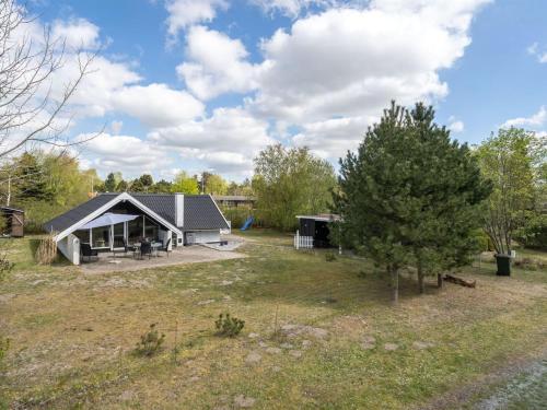 a house with a black roof in a field at Holiday Home Arnfin - 160m from the sea by Interhome in Rødby