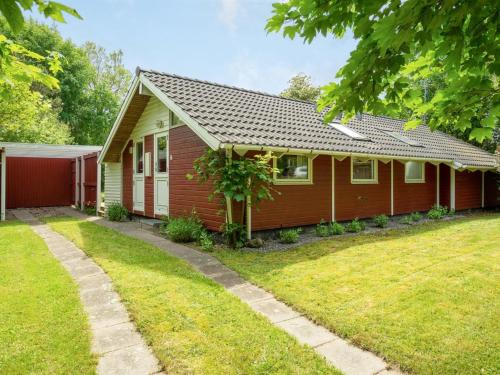 a red house with a grass yard in front of it at Holiday Home Maard - 325m from the sea by Interhome in Martofte
