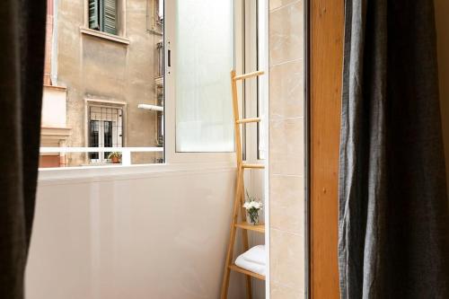 um quarto com uma janela com uma cadeira e uma escada em Lodging Apartments Barceloneta Mar em Barcelona