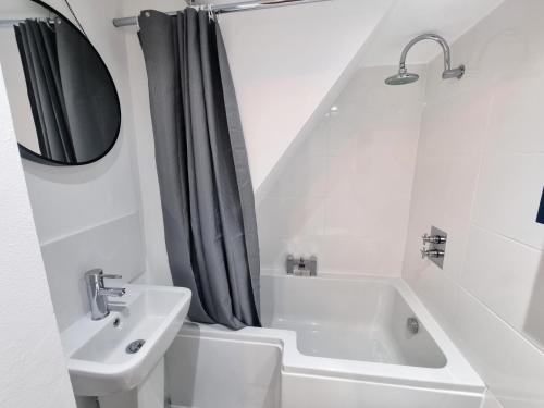 SPACIOUS 3 Bed APARTMENT WITH EN-SUITES في واتفورد: حمام أبيض مع حوض وحوض استحمام