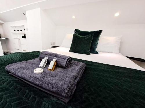 a bed with a green blanket and two bottles of perfume at SPACIOUS 3 Bed APARTMENT WITH EN-SUITES in Watford