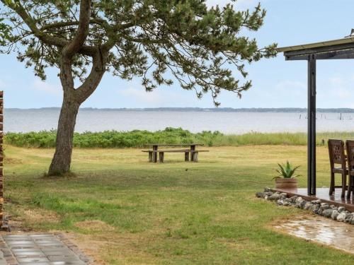 a picnic table and a tree next to the water at Holiday Home Sigurd - 20m from the sea in Funen by Interhome in Middelfart