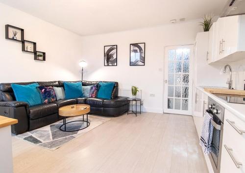 a living room with a black leather couch and a table at SPACIOUS 3 Bed APARTMENT, EN-SUITES, NEAR TRAIN STATION! in Watford