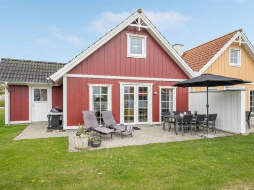 uma casa vermelha com uma mesa e cadeiras e um guarda-sol em Holiday Home Askan - 200m from the sea in Funen by Interhome em Bro