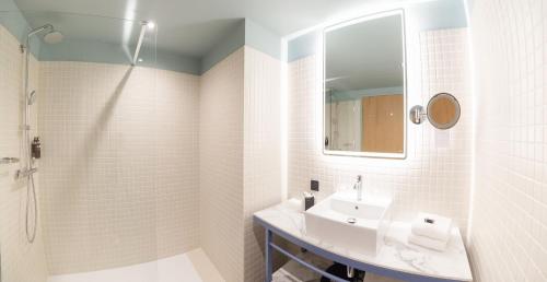 a white bathroom with a sink and a mirror at KOPSTER Hotel Residence Paris Ouest Colombes in Colombes