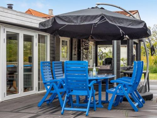 une table bleue et des chaises sous un parasol sur une terrasse dans l'établissement Holiday Home Hardina - 300m from the sea in Funen by Interhome, à Martofte