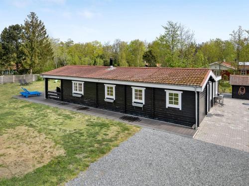 une petite cabine noire avec un toit rouge dans l'établissement Holiday Home Hardina - 300m from the sea in Funen by Interhome, à Martofte