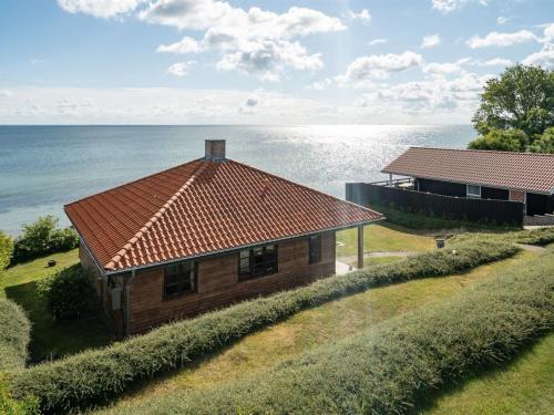 Ullerslev的住宿－Holiday Home Botmar - 10m from the sea in Funen by Interhome，一座山丘上的房屋,背景是大海