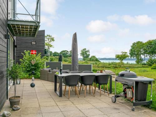 un patio con tavolo, sedie e griglia di Holiday Home Anny - 100m from the sea in Funen by Interhome ad Asperup