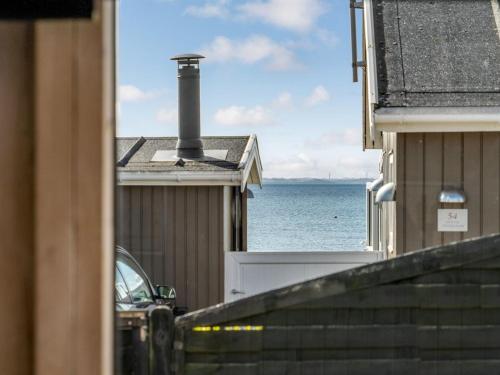 a view of the ocean from between buildings at Holiday Home Loella - 35m from the sea in Funen by Interhome in Svendborg