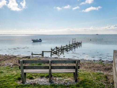 a wooden bench sitting on the shore of a body of water at Holiday Home Loella - 35m from the sea in Funen by Interhome in Svendborg