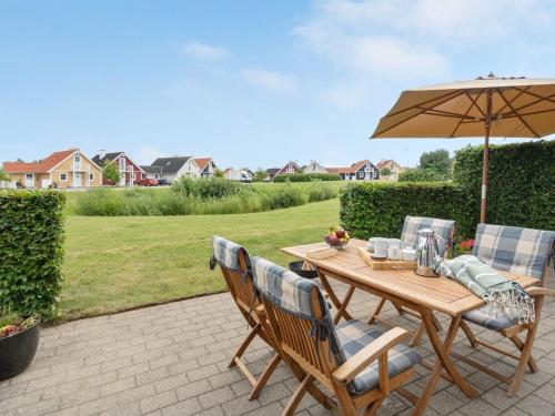 einen Holztisch und Stühle mit Sonnenschirm in der Unterkunft Holiday Home Eike - 250m from the sea in Funen by Interhome in Bro