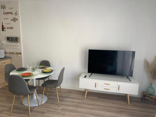 a living room with a table with chairs and a tv at Apartamento Peñas Blancas, junto a ruta de los Cahorros, Monachil. in Monachil