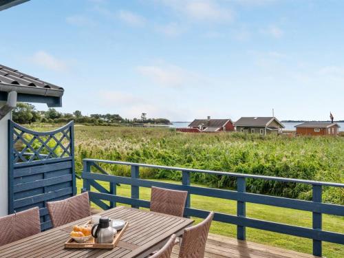 een houten tafel en stoelen op een terras met een veld bij Holiday Home Herulf - 100m from the sea by Interhome in Bogentved