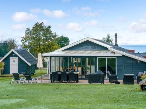 une maison bleue avec des chaises et des tables dans une cour dans l'établissement Holiday Home Fita - 300m from the sea in Funen by Interhome, à Asperup