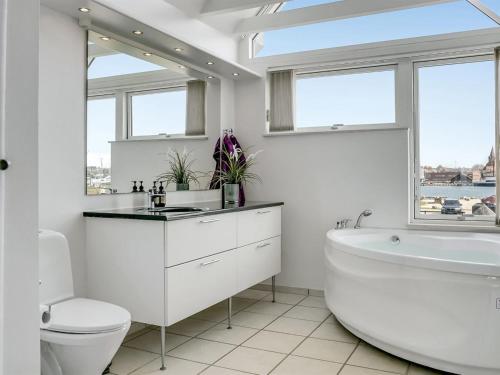 een witte badkamer met een bad, een toilet en een wastafel bij Apartment Ninne - 50m from the sea in Funen by Interhome in Assens