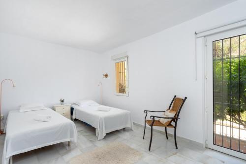 Habitación blanca con 2 camas y silla en Lovely flat in Casinomar - Torrequebrada Ref 114, en Benalmádena