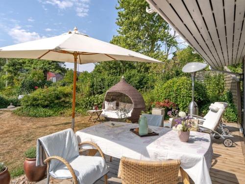 un patio con una mesa con una sombrilla y una parrilla en Holiday Home Daike - 25m from the sea in Funen by Interhome, en Bogentved