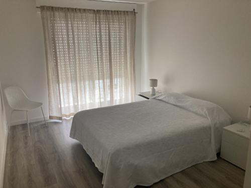 a white bedroom with a bed and a window at Casa da Marina in Esposende