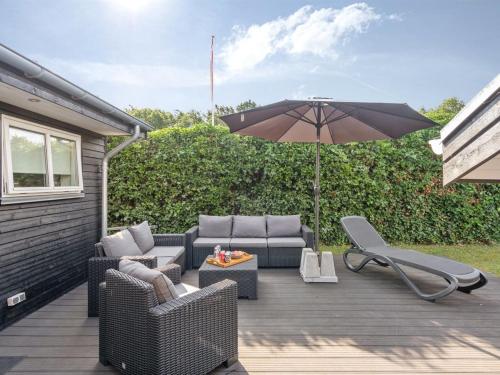 a patio with two couches and an umbrella at Holiday Home Kamilla - 200m from the sea in Funen by Interhome in Nyborg