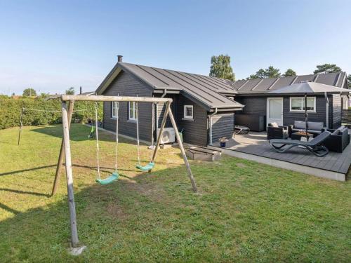 a swing in a yard in front of a house at Holiday Home Kamilla - 200m from the sea by Interhome in Nyborg