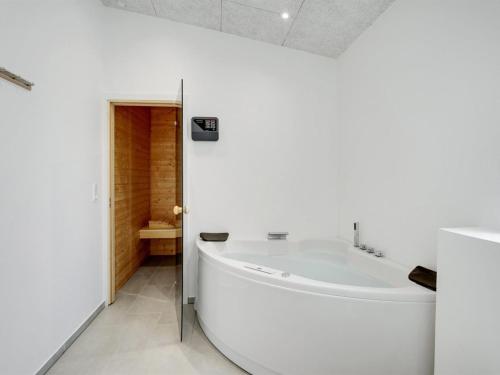 a white bathroom with a tub and a toilet at Holiday Home Constantin - 500m from the sea by Interhome in Sjølund
