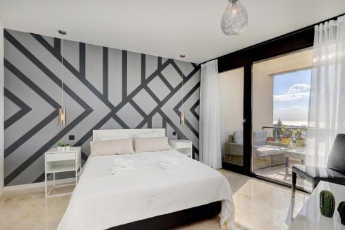 una camera da letto con un letto bianco con una parete a righe di Modern, elite hillside home w/sea & mountain views a Marbella