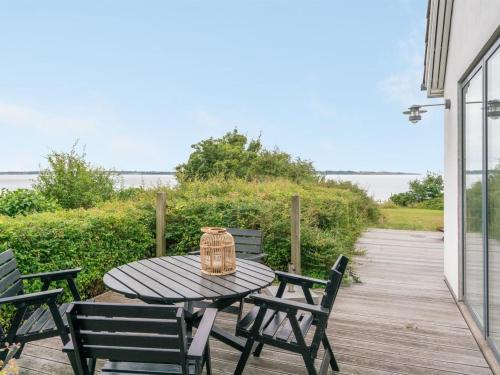 een picknicktafel met stoelen en een mand op een veranda bij Holiday Home Sissela - 5m from the sea in Funen by Interhome in Ebberup
