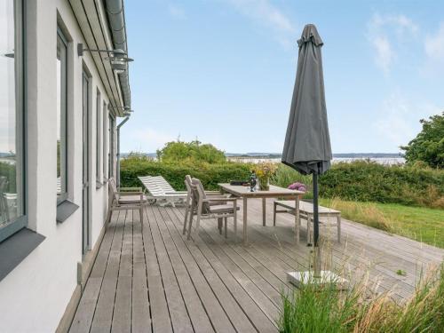 a wooden deck with a table and an umbrella at Holiday Home Sissela - 5m from the sea by Interhome in Ebberup