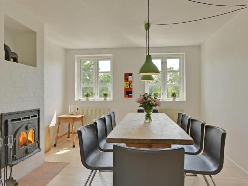 una sala da pranzo con tavolo, sedie e camino di Holiday Home Ansbert - 150m from the sea in Funen by Interhome ad Assens