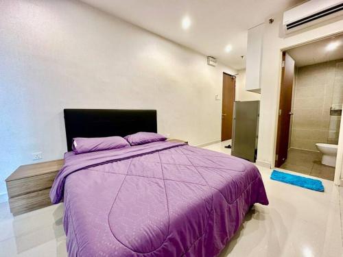 a bedroom with a purple bed and a bathroom at Kuching Kozi Square Apartment in Kuching
