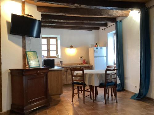 une cuisine avec une table, des chaises et un réfrigérateur dans l'établissement La maisonnette des champs, à Pierre-Buffière