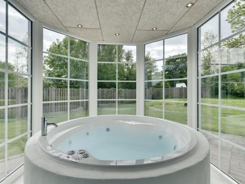 a large bath tub in a room with windows at Holiday Home Gunhilda - 200m from the sea in Funen by Interhome in Spodsbjerg