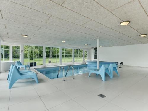a swimming pool with blue chairs in a building at Holiday Home Gunhilda - 200m from the sea in Funen by Interhome in Spodsbjerg