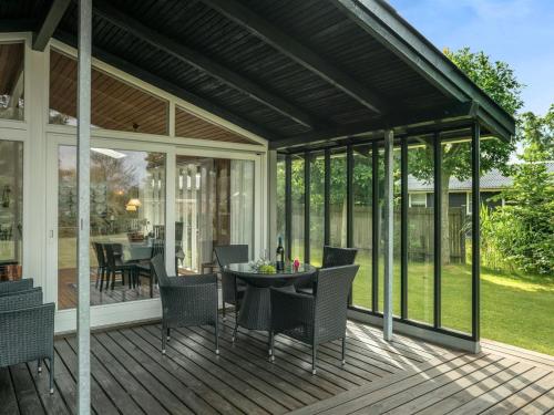 a screened in porch with a table and chairs at Holiday Home Juditha - 400m from the sea in Funen by Interhome in Middelfart