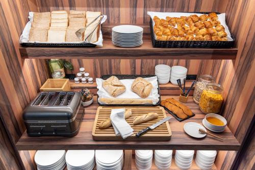a shelf with bread and other food on it at KOPSTER Hotel Residence Paris Ouest Colombes in Colombes