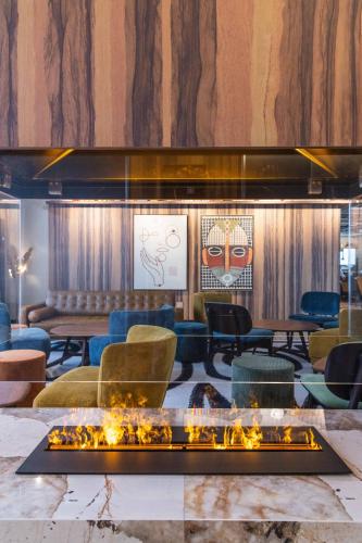 a lobby with a fireplace and tables and chairs at KOPSTER Hotel Residence Paris Ouest Colombes in Colombes