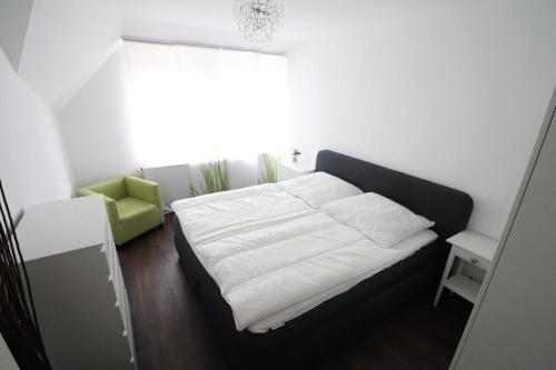 um quarto com uma cama branca e uma cadeira verde em Wernerwaldstr-1 em Cuxhaven