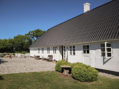 a white building with a black roof and a yard at Holiday Home Harre - 300m from the sea in Funen by Interhome in Rudkøbing