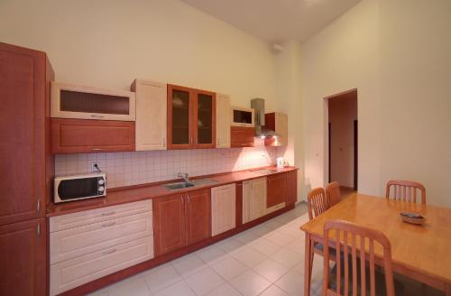 a kitchen with wooden cabinets and a table with a microwave at Slunecni Lazne Apartments in Karlovy Vary