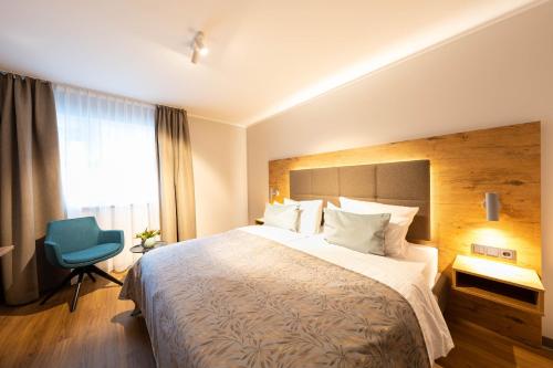 a hotel room with a large bed and a blue chair at Sopherl am See - Frühstück auf der Seeterrasse, sehr ruhig und wunderschön am See, 3 Minuten nach Oberpfaffenhofen, viele Radtouren, Restaurants & Cafes in der Umgebung in Weßling