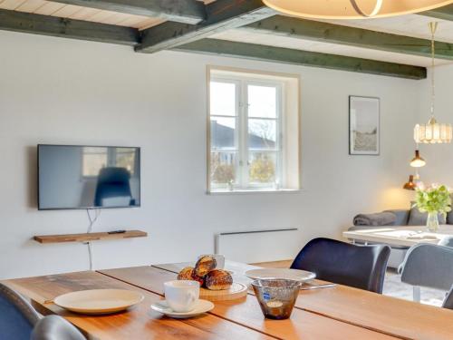 uma sala de jantar com uma mesa de madeira e uma televisão em Holiday Home Nita - 24km from the sea in Western Jutland by Interhome em Højer