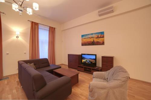 a living room with a couch and a tv at Slunecni Lazne Apartments in Karlovy Vary