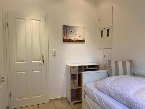 1 dormitorio con cama, escritorio y puerta en Ferienhaus Lammertshörn Bensersiel en Bensersiel