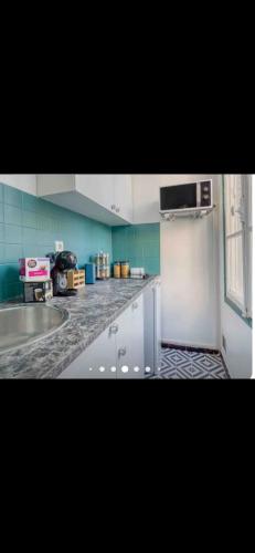 une cuisine avec des armoires blanches et un mur bleu dans l'établissement le Petit nid d'amour, à Le Pré-Saint-Gervais