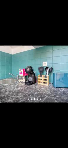 Il comprend une cuisine dotée d'un mur carrelé bleu et d'un comptoir. dans l'établissement le Petit nid d'amour, à Le Pré-Saint-Gervais