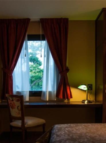 a bedroom with a bed and a window with a chair at Hotel City Bell in La Plata