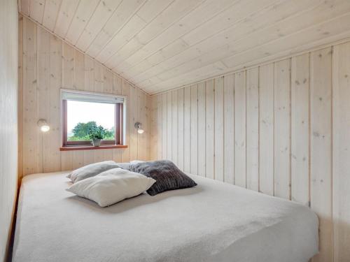 a bed in a room with wooden walls and a window at Holiday Home Juliana - 400m from the sea by Interhome in Nordborg